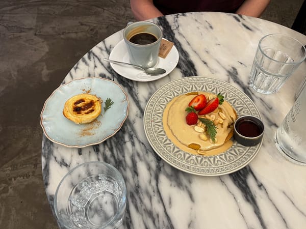 An image of pastel-de-nata on a blue plate next to some pancakes in a restaurant in Lisbon